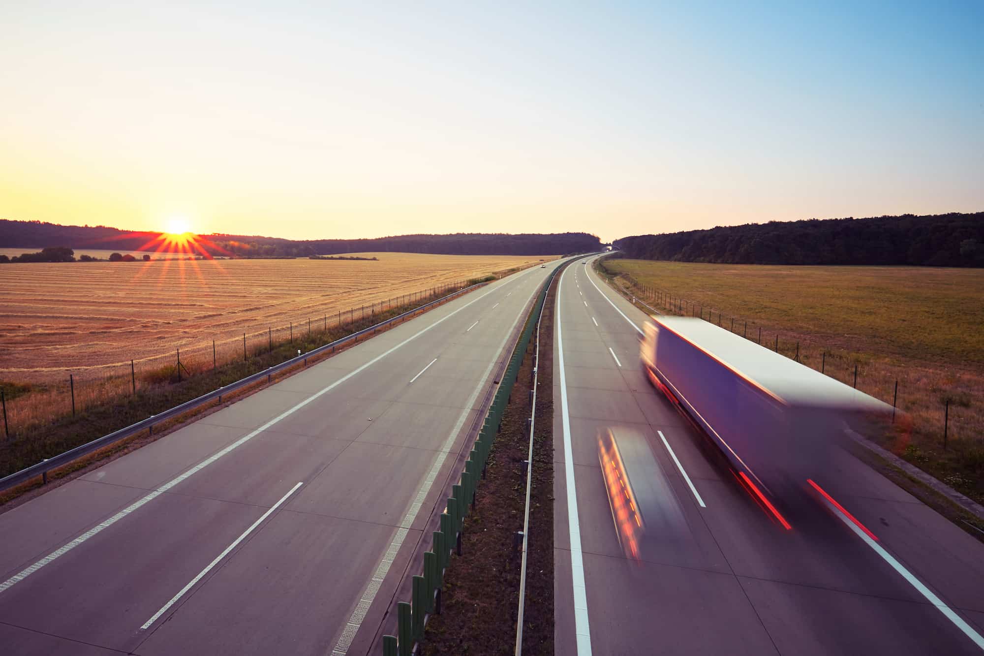 Cargo trucks travelling on a motorway at dusk